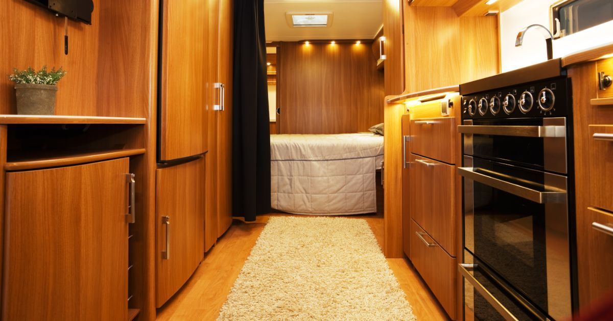 A kitchen with a stove and a bed in the background