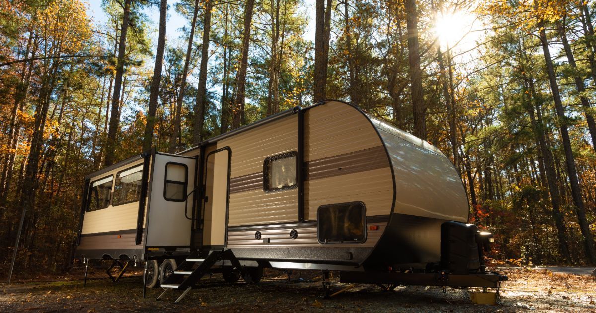 A large rv is parked in a grassy area next to a picnic table.