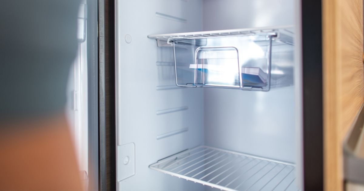 A close up of an empty refrigerator with a glass door.