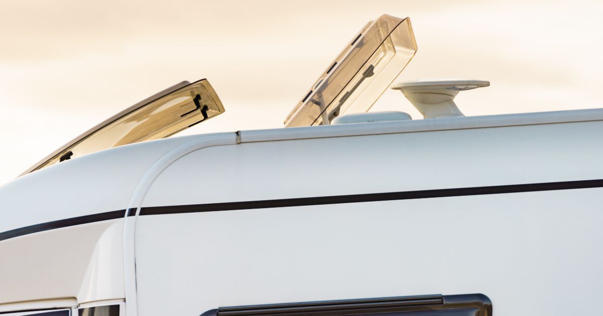 A white camper van with a roof window open.