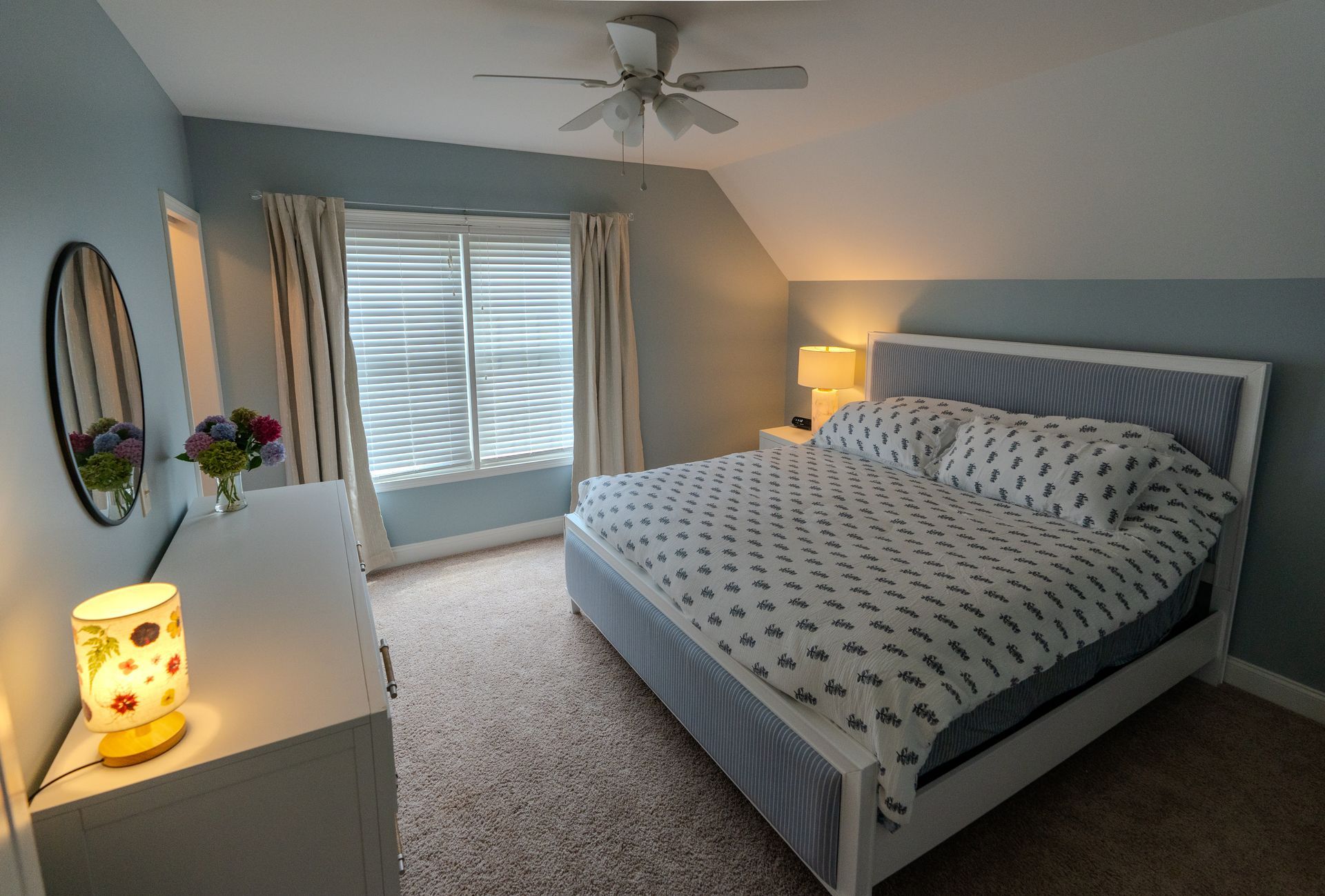 Bedroom with bed, dresser, and window, in shades of blue and white.