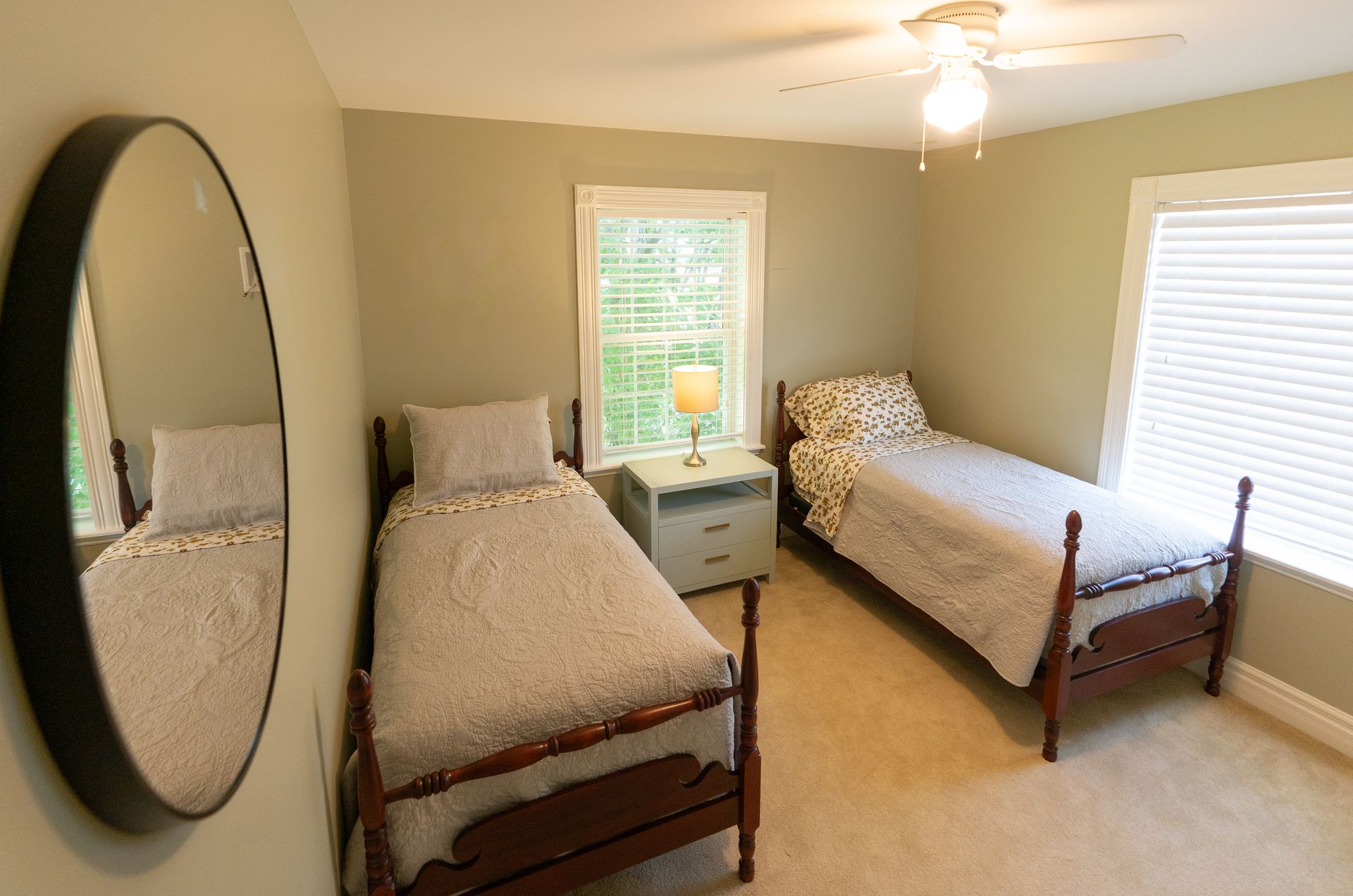 Bedroom with two twin beds, nightstand, mirror, and two windows.