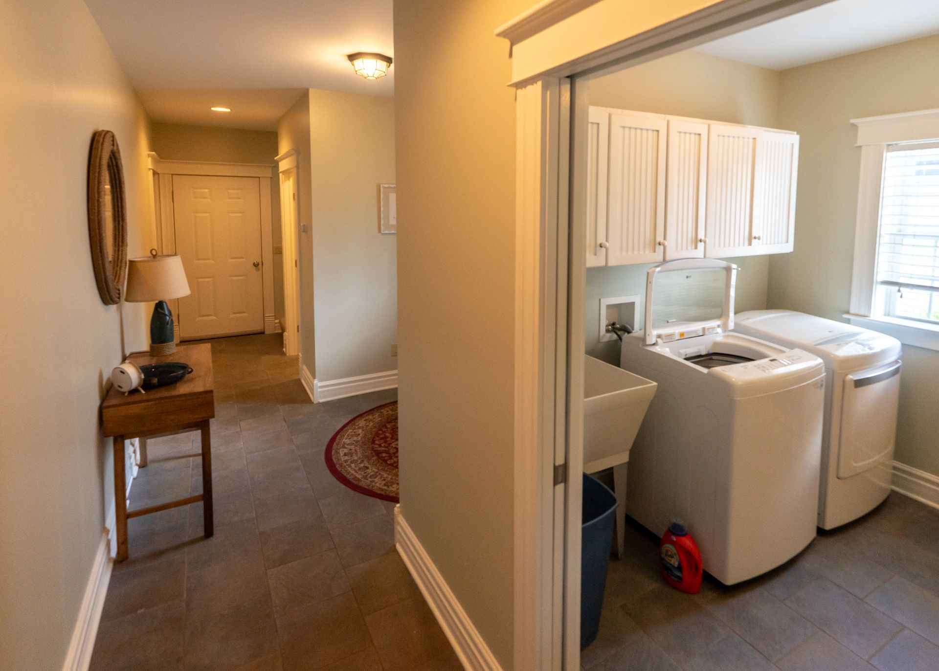 Hallway with laundry room on the right, featuring a washer, dryer, and sink.