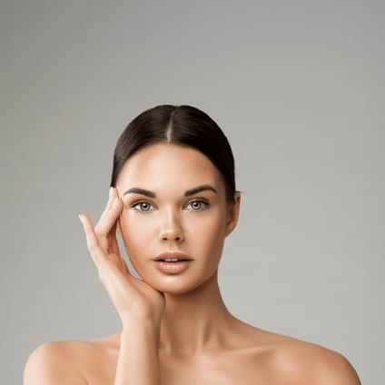 A woman is touching her face with her hand and looking at the camera.