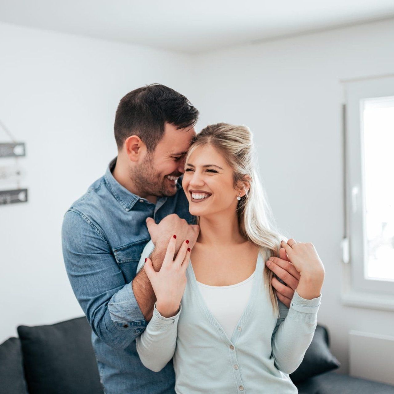 A man and a woman are hugging each other in a living room.