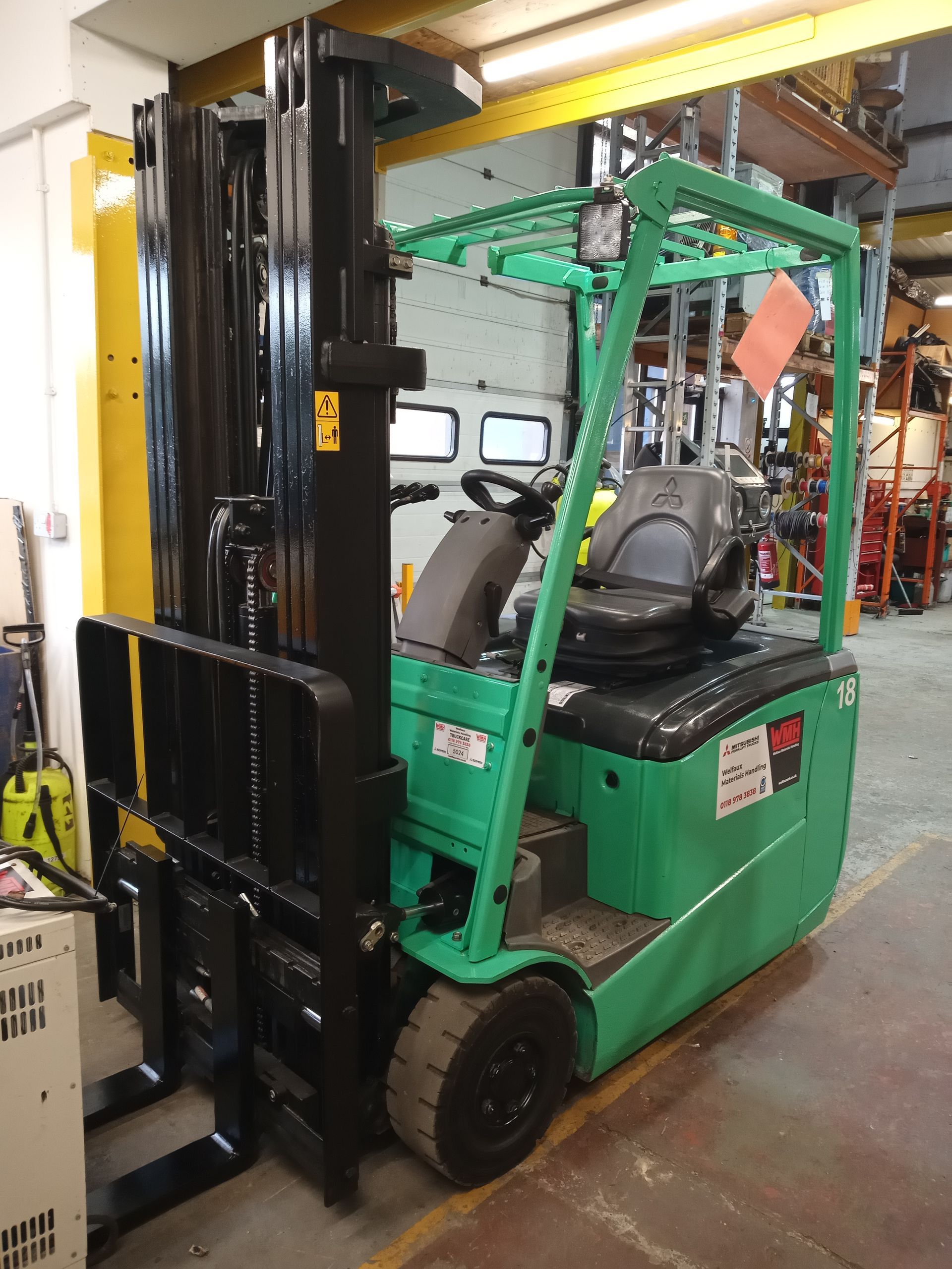 A green forklift is parked in a warehouse