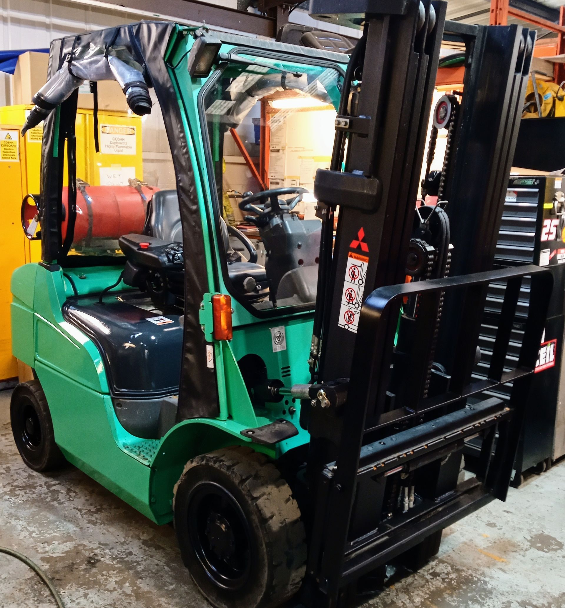 A green and black forklift is parked in a garage