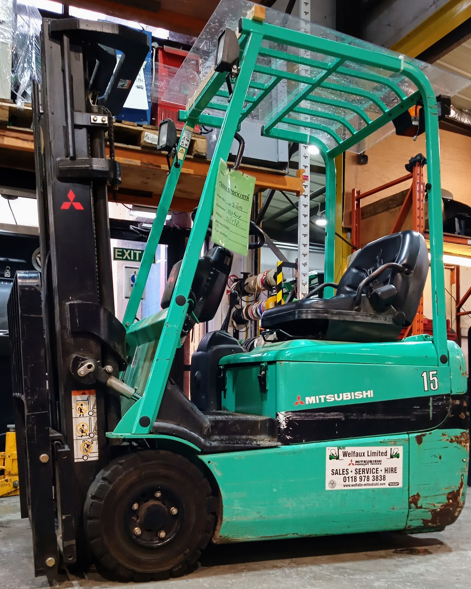 A green and black forklift is parked in a warehouse
