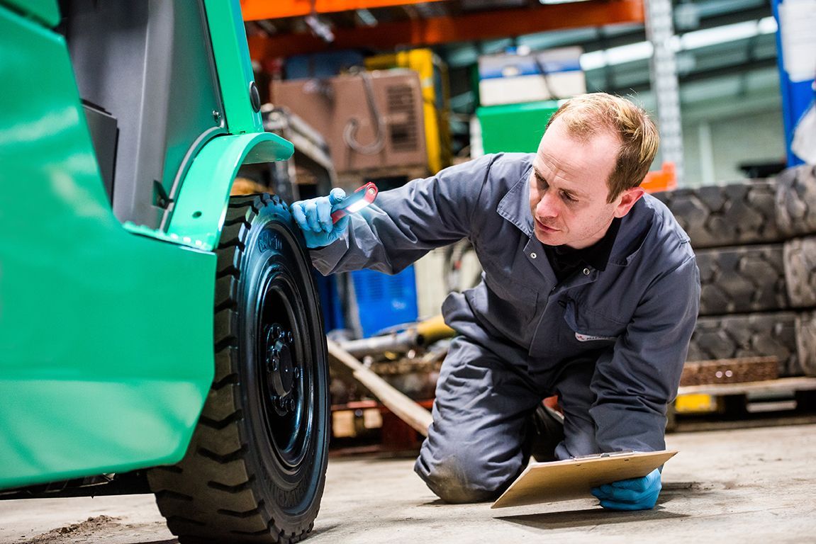 Man in overalls servicing a Mitsubishi forklift