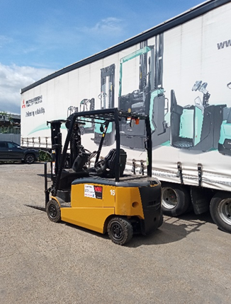 A yellow forklift is parked in front of a large white truck.