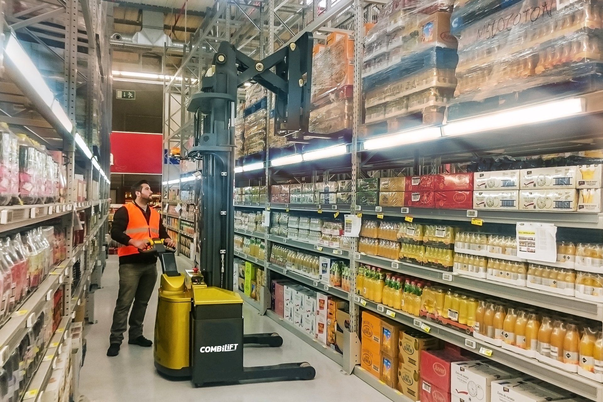Man operating a Combilift stacker forklift in the food and drink aisle of a warehouse