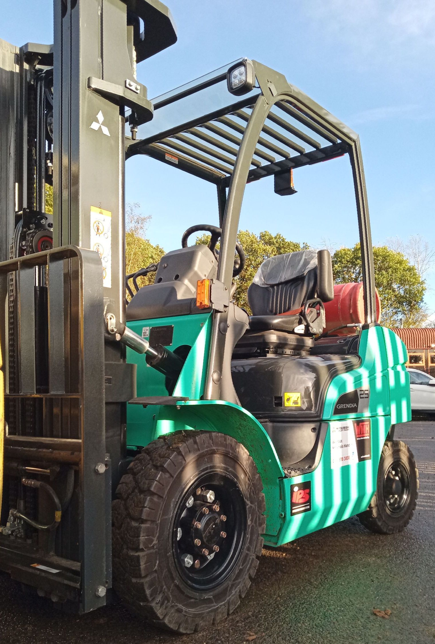 A green and black forklift is parked in a parking lot.
