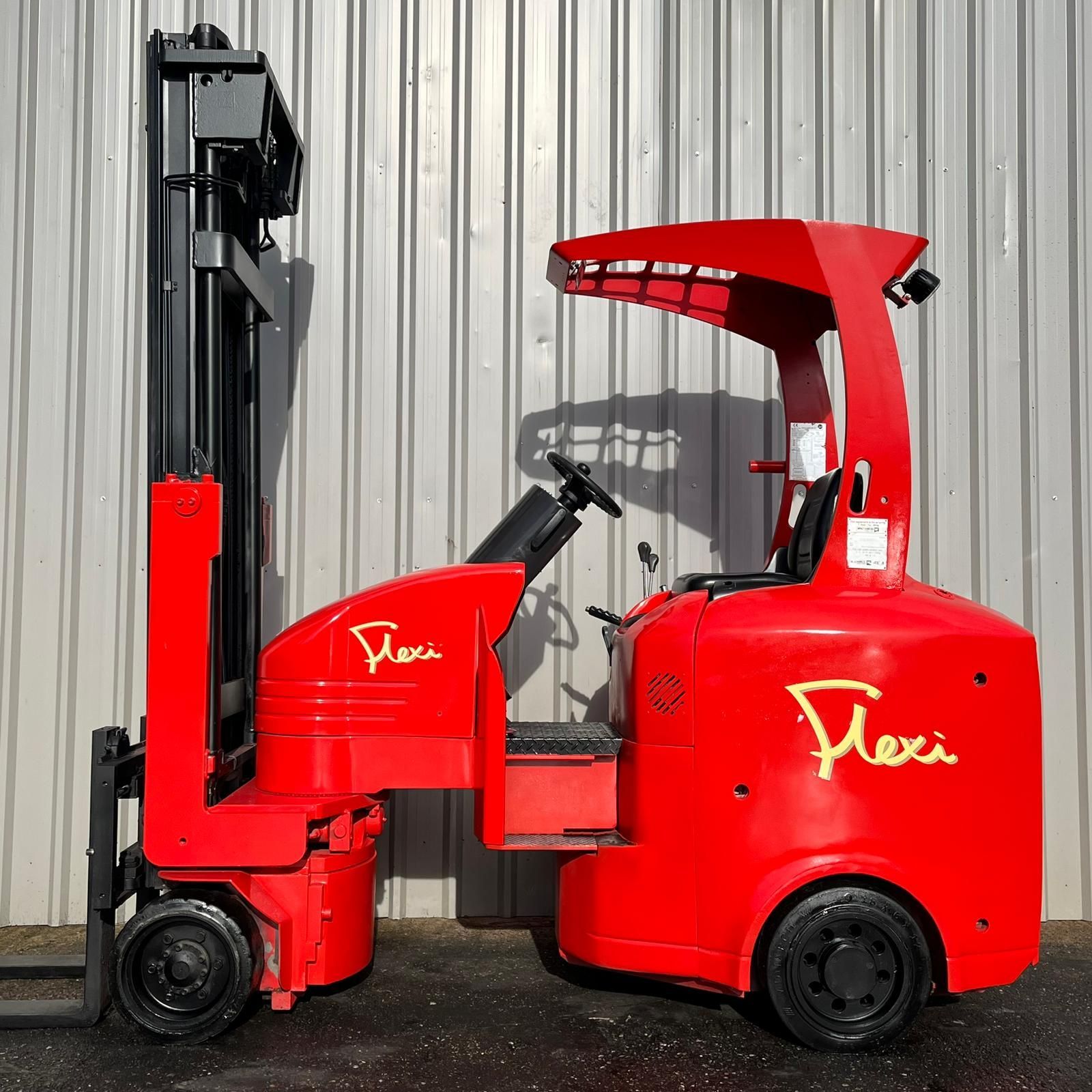 A red flexi forklift is parked in front of a building