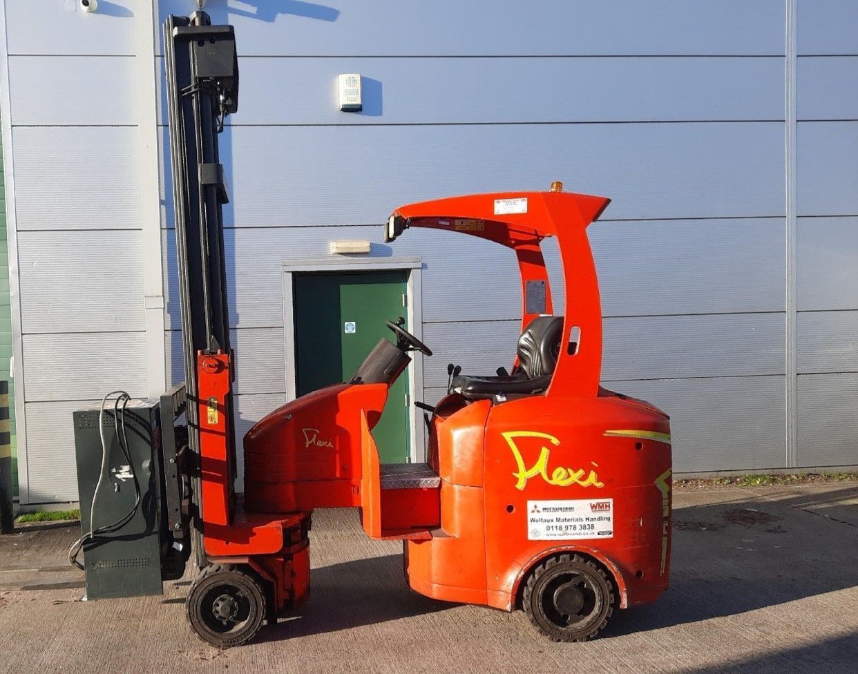 A red forklift is parked in front of a building