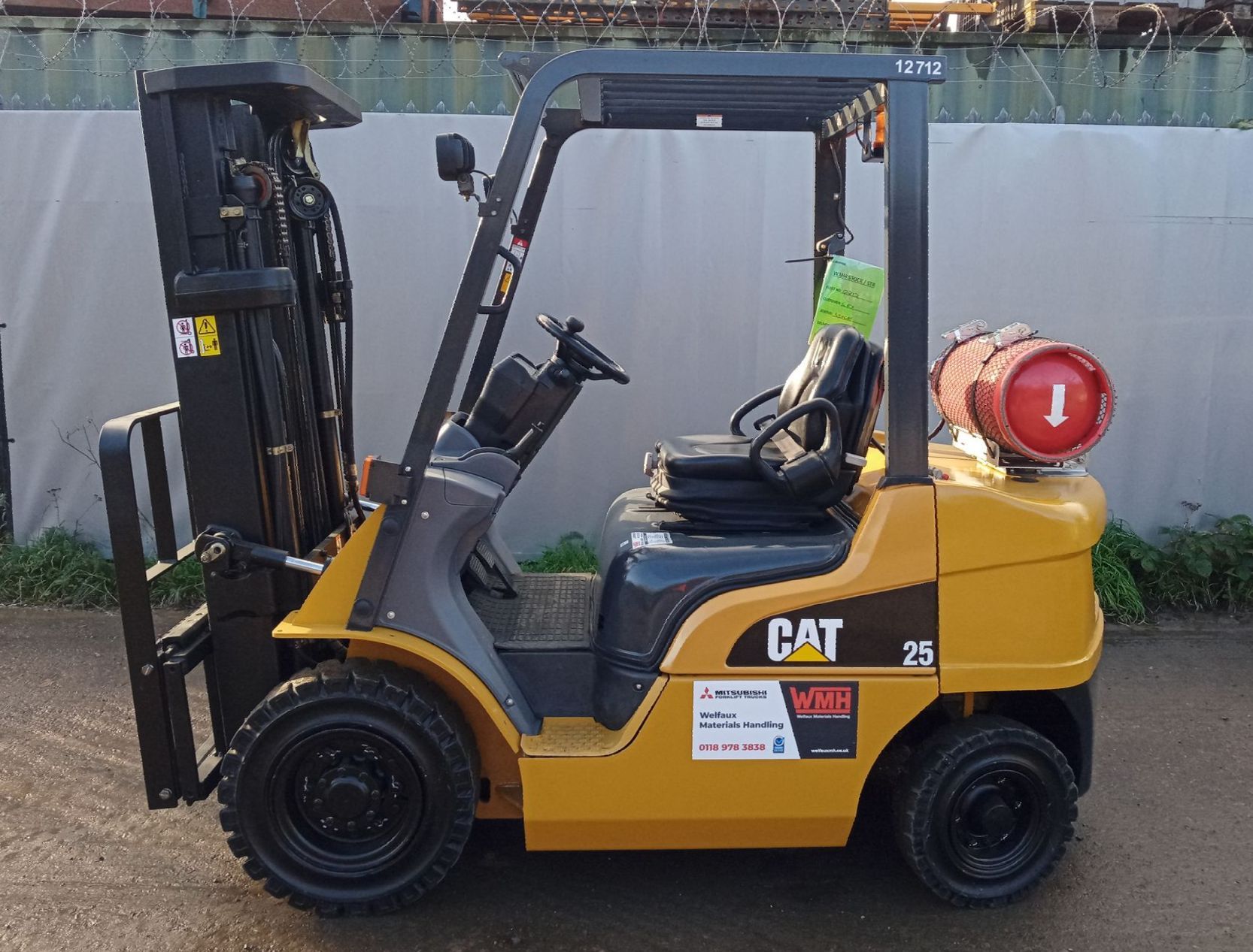 A yellow and black cat forklift is parked on the side of the road
