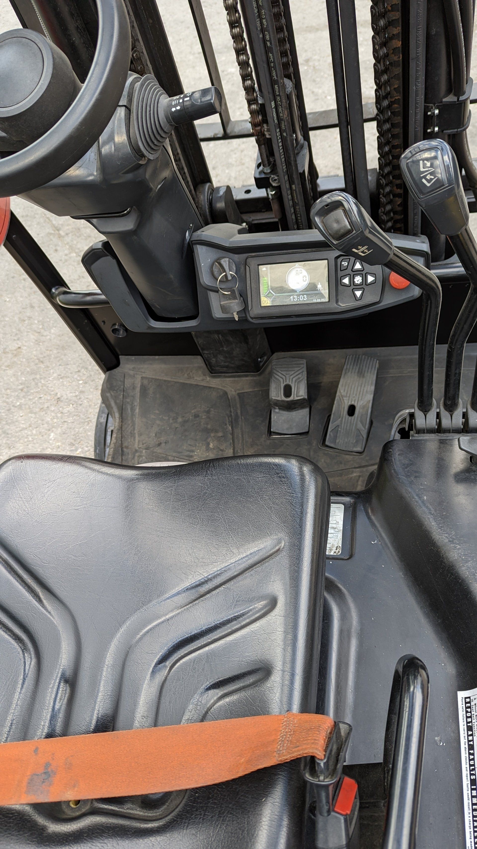 The inside of a forklift with a seat and steering wheel. Mitsubishi