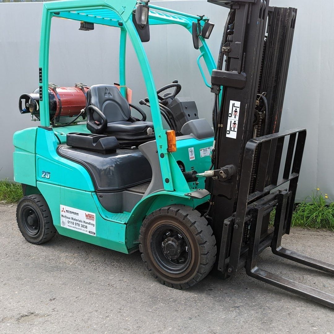 A green forklift is parked on the side of the road.