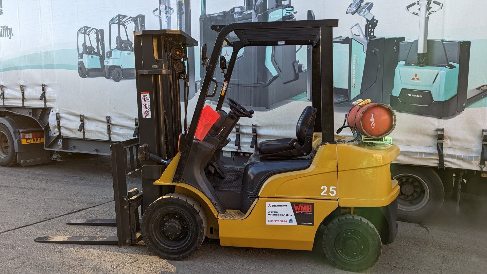 A yellow forklift is parked in front of a truck.