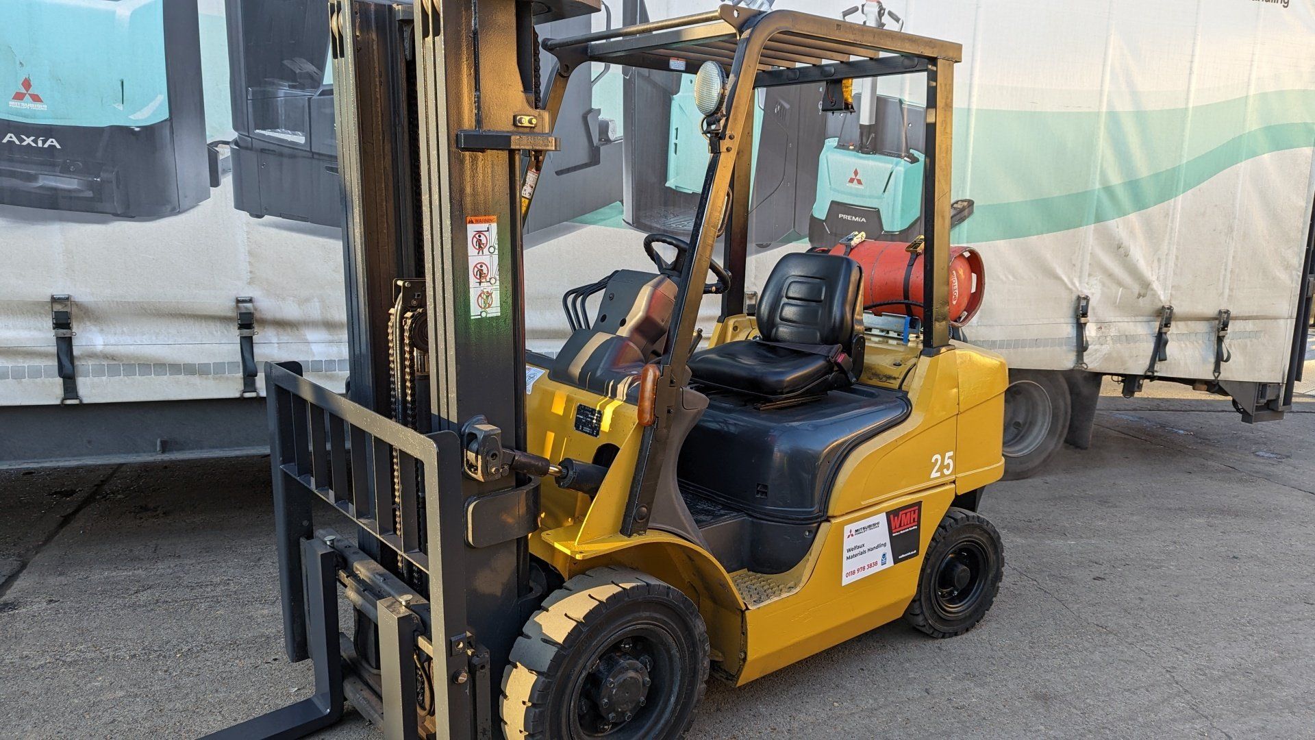 A yellow forklift is parked in front of a truck.