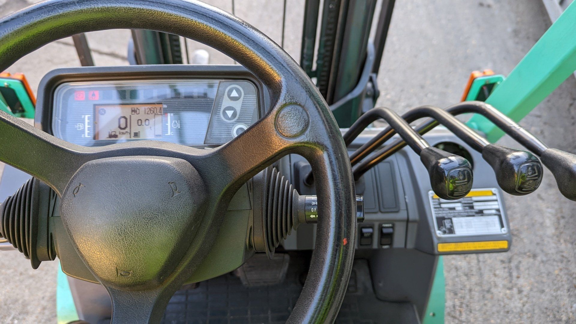 The inside of a forklift with a steering wheel and controls.