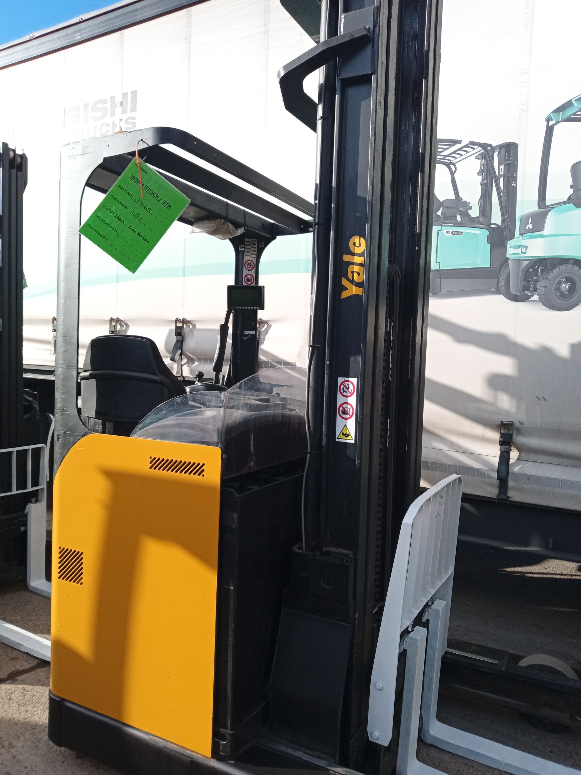 A yellow and black forklift is parked in front of a white truck.