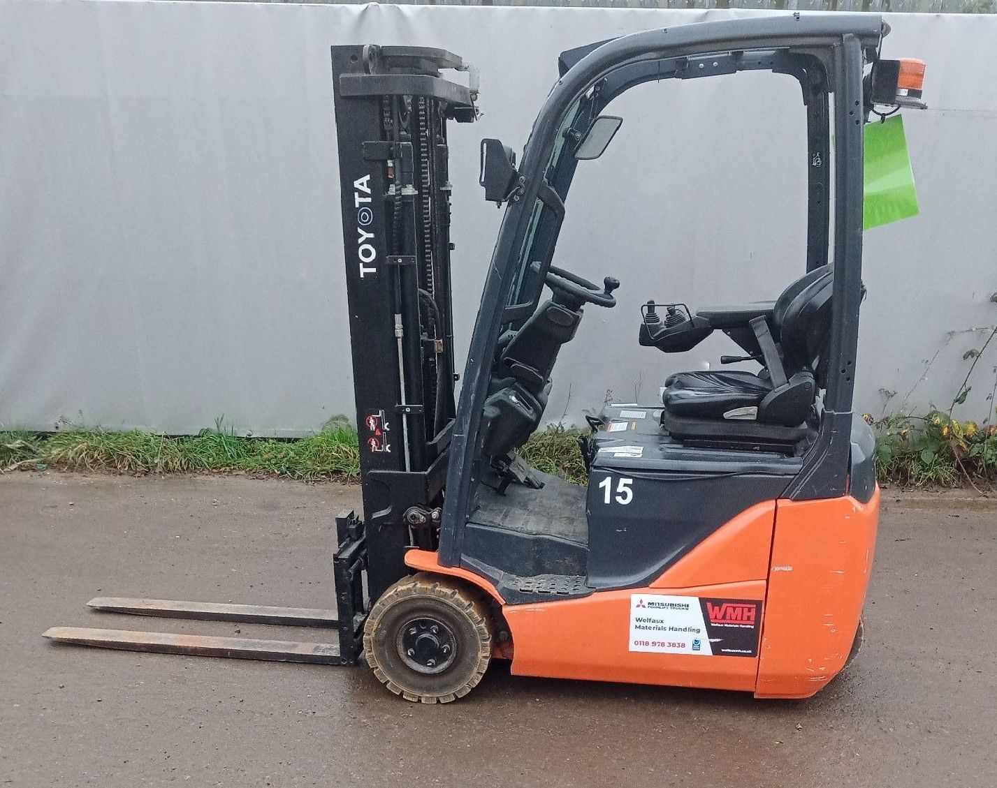 A green forklift is parked on the side of the road.