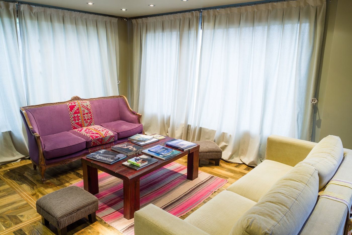 Una sala de estar con un sofá morado y un sofá blanco y una mesa de café.