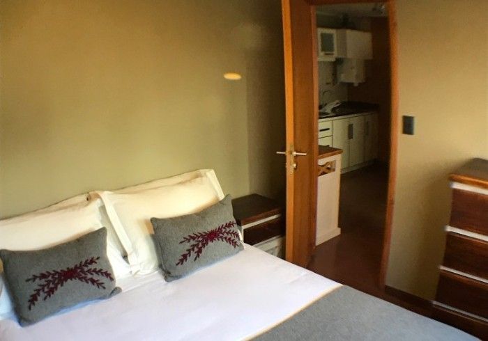 Un dormitorio con una cama y una puerta que conduce a una cocina.