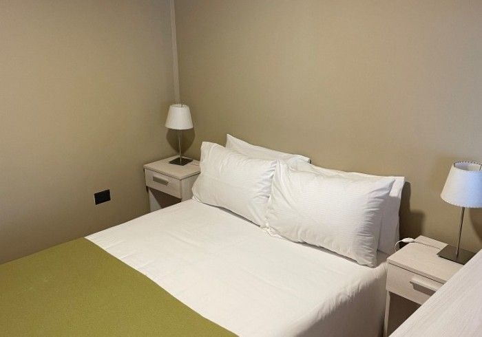 Un dormitorio con una cama, dos mesitas de noche y dos lámparas.