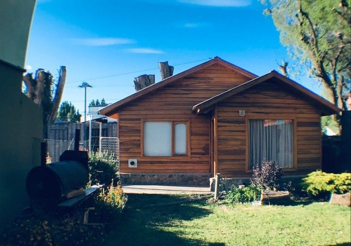 Una pequeña casa de madera con una parrilla delante de ella.