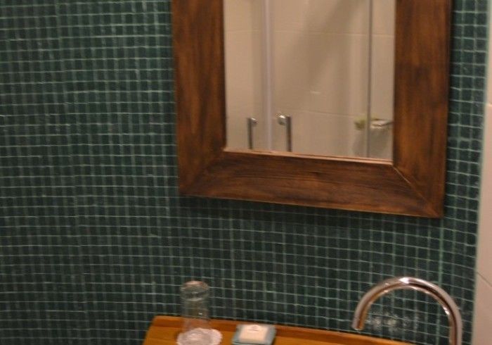 Un baño con lavabo, espejo y azulejos verdes.