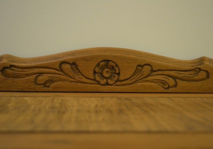 Un estante de madera con una flor tallada en él.
