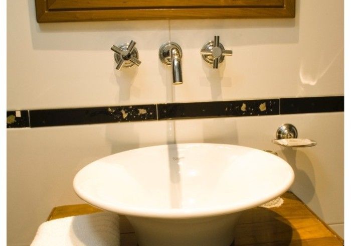 Un lavabo de baño con tres grifos y un espejo.