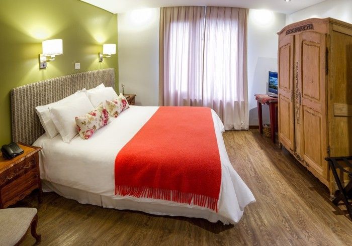 Una habitación de hotel con una cama tamaño king y un armario de madera.
