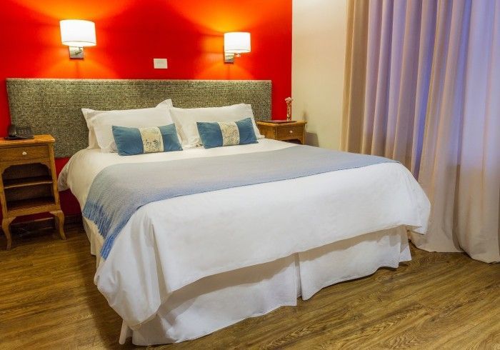 Una habitación de hotel con una cama tamaño king y una pared roja.