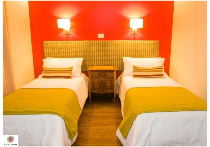 Un dormitorio con dos camas y una pared roja.