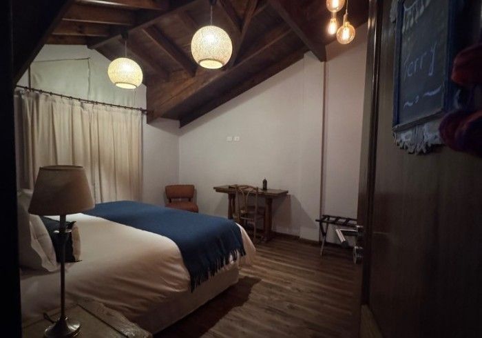 Un dormitorio con una cama, una lámpara y una silla.