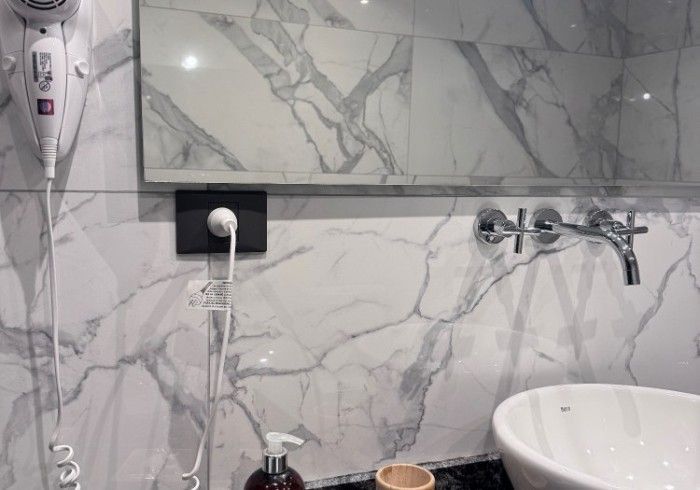 Un baño con lavabo, espejo y secador de pelo.