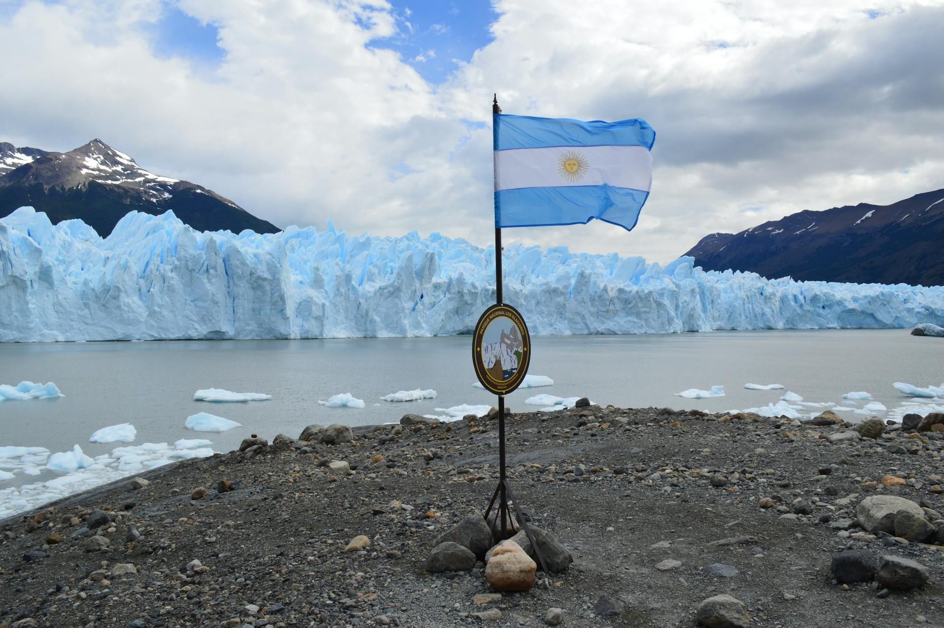 Una bandera argentina ondea frente a un glaciar.