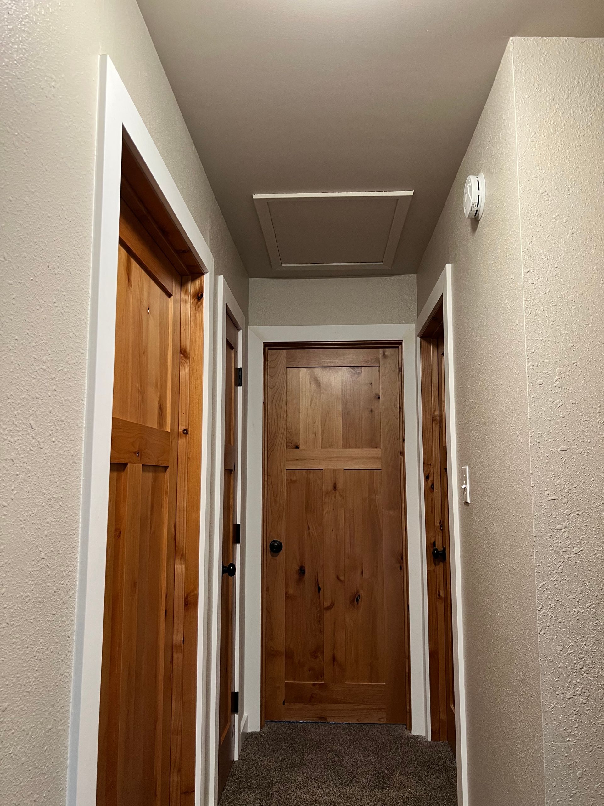 A hallway with wooden doors and a ceiling fan.