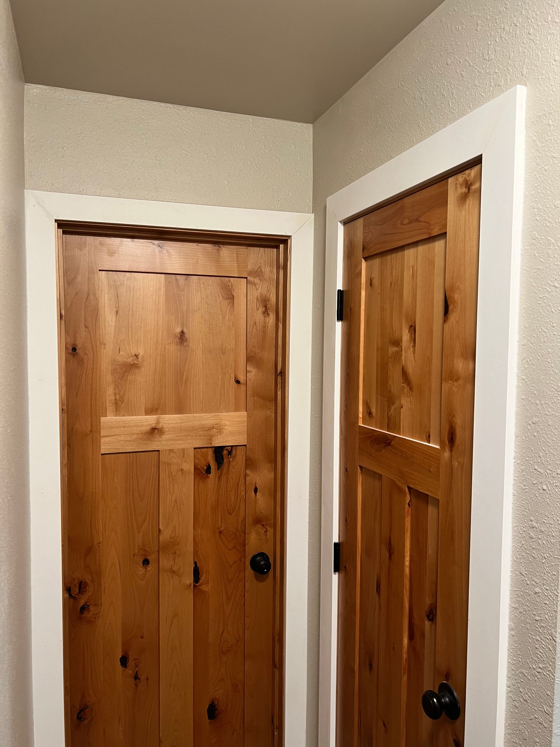 Two wooden doors are sitting next to each other in a hallway.