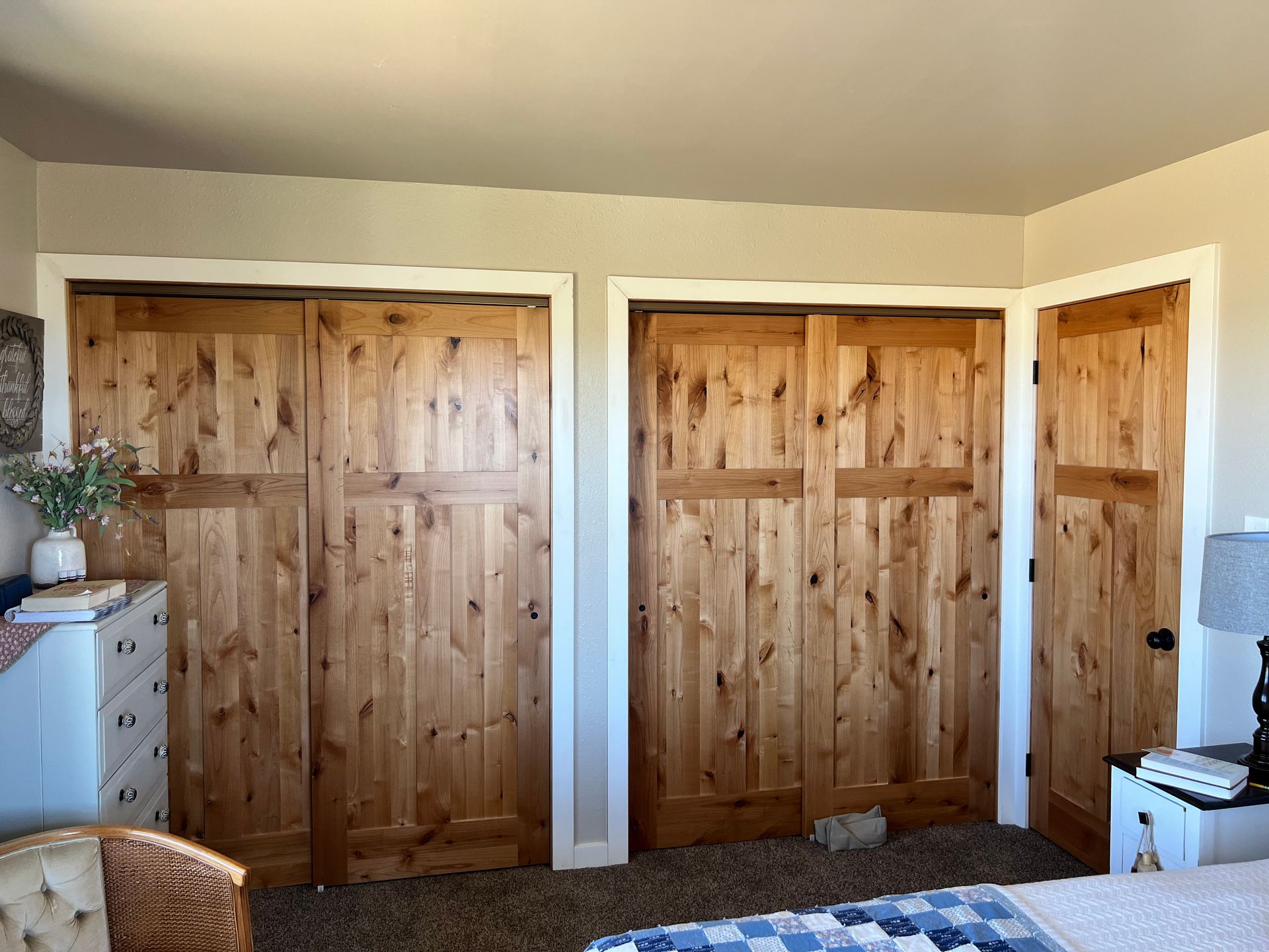 A bedroom with lots of wooden doors and a bed.
