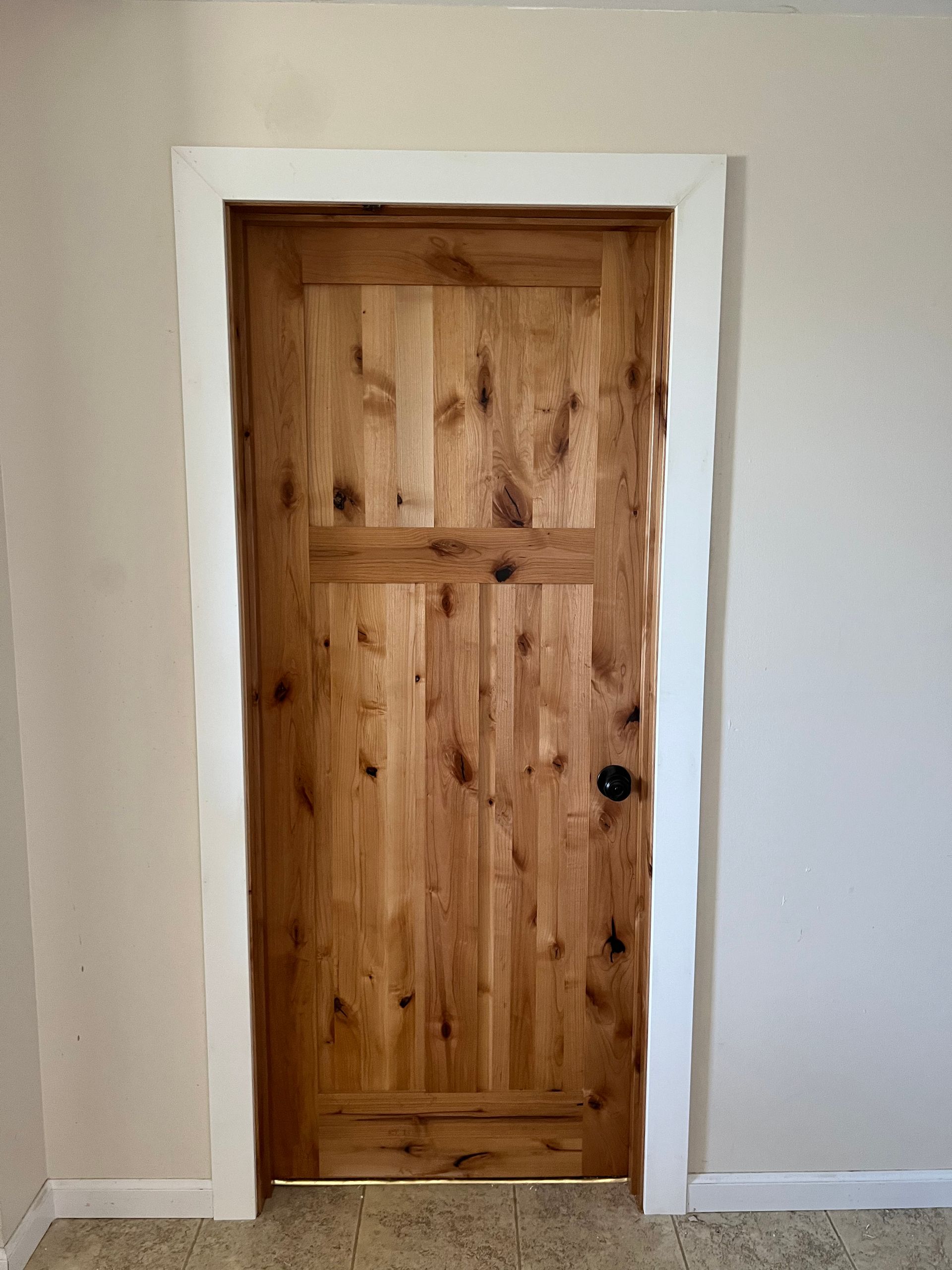 A wooden door with a white trim is in a room.