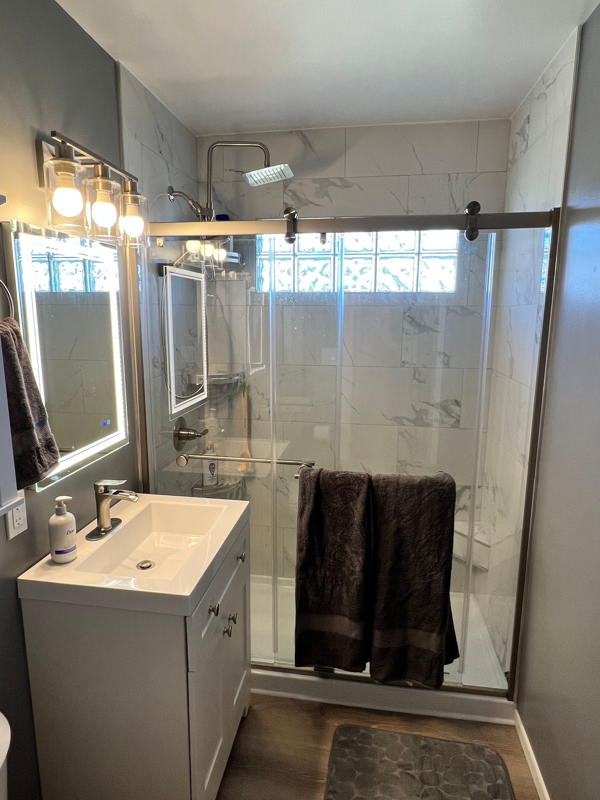 A bathroom with a sink , mirror , and shower stall.