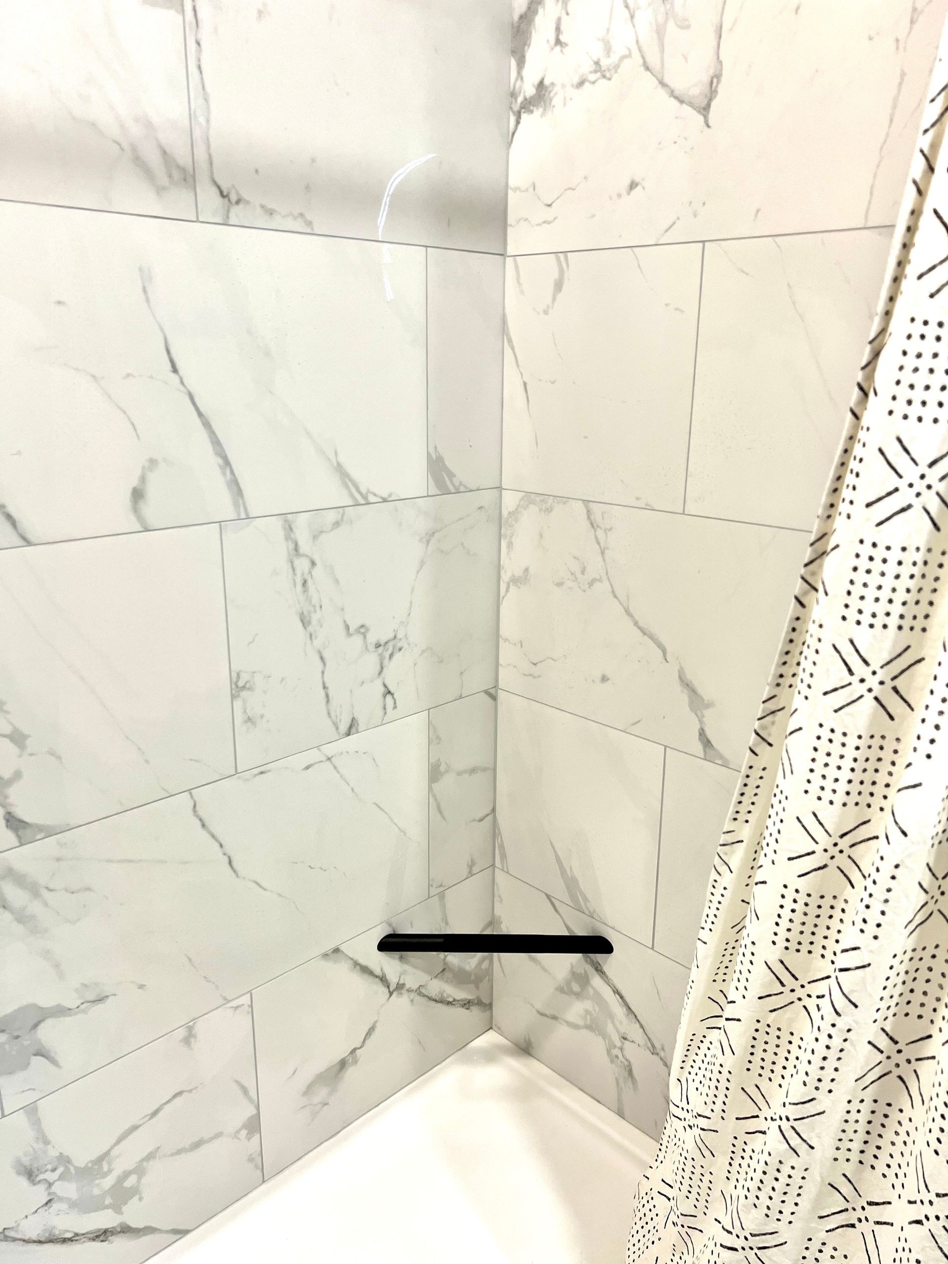 A bathroom with marble tiles and a shower curtain.