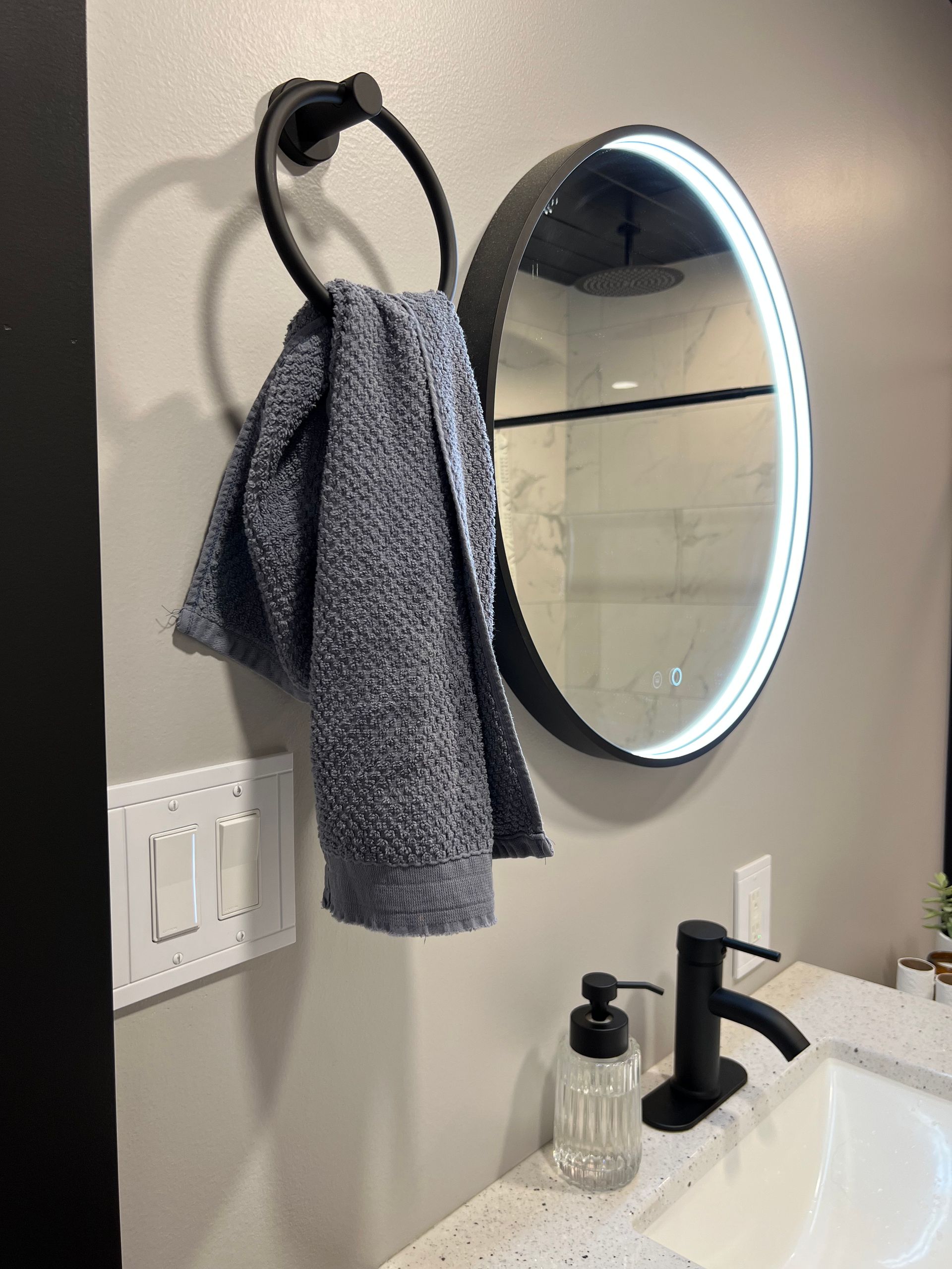 A towel is hanging on a towel ring in a bathroom next to a mirror.
