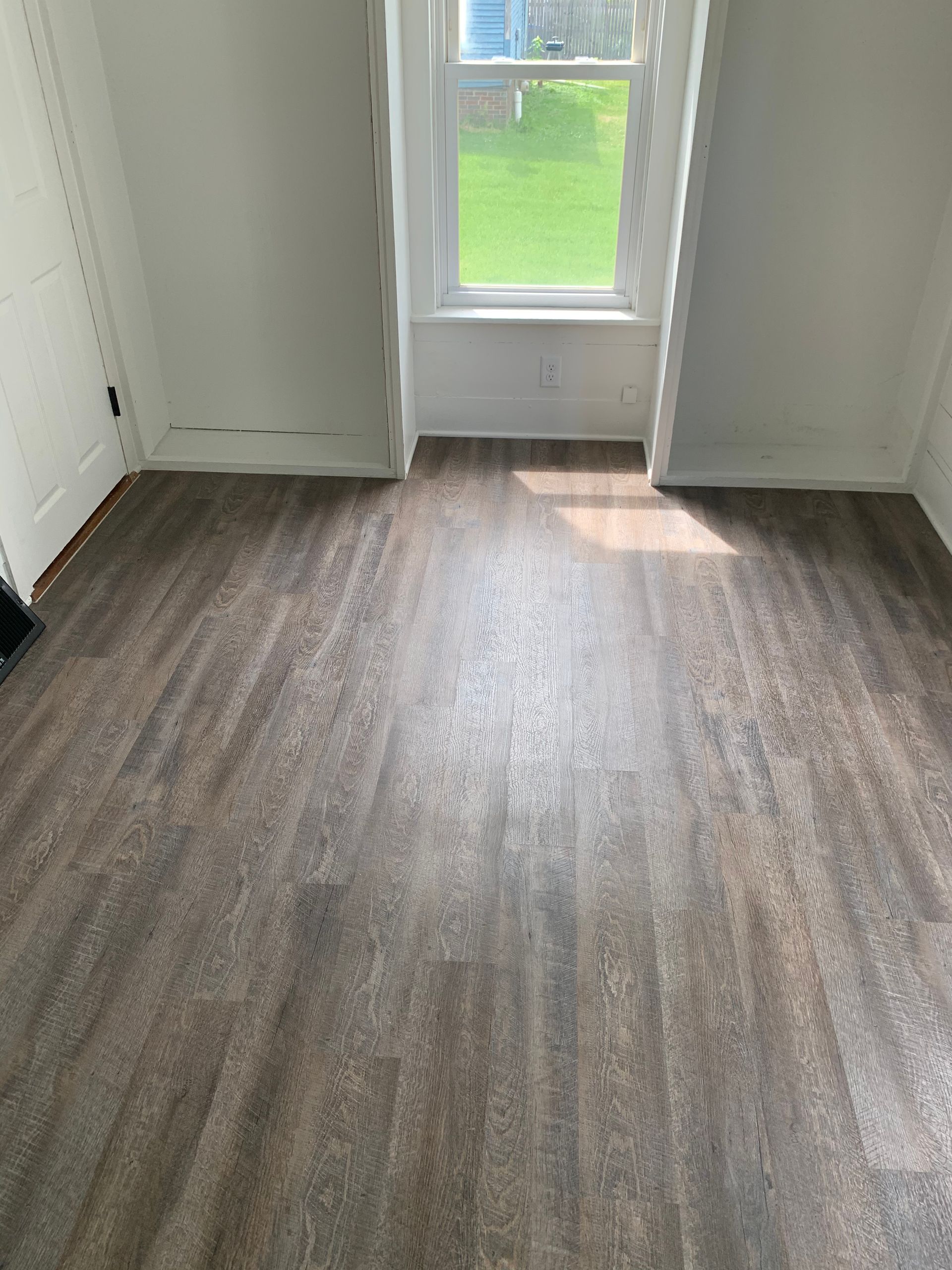 A room with a wooden floor and a window.