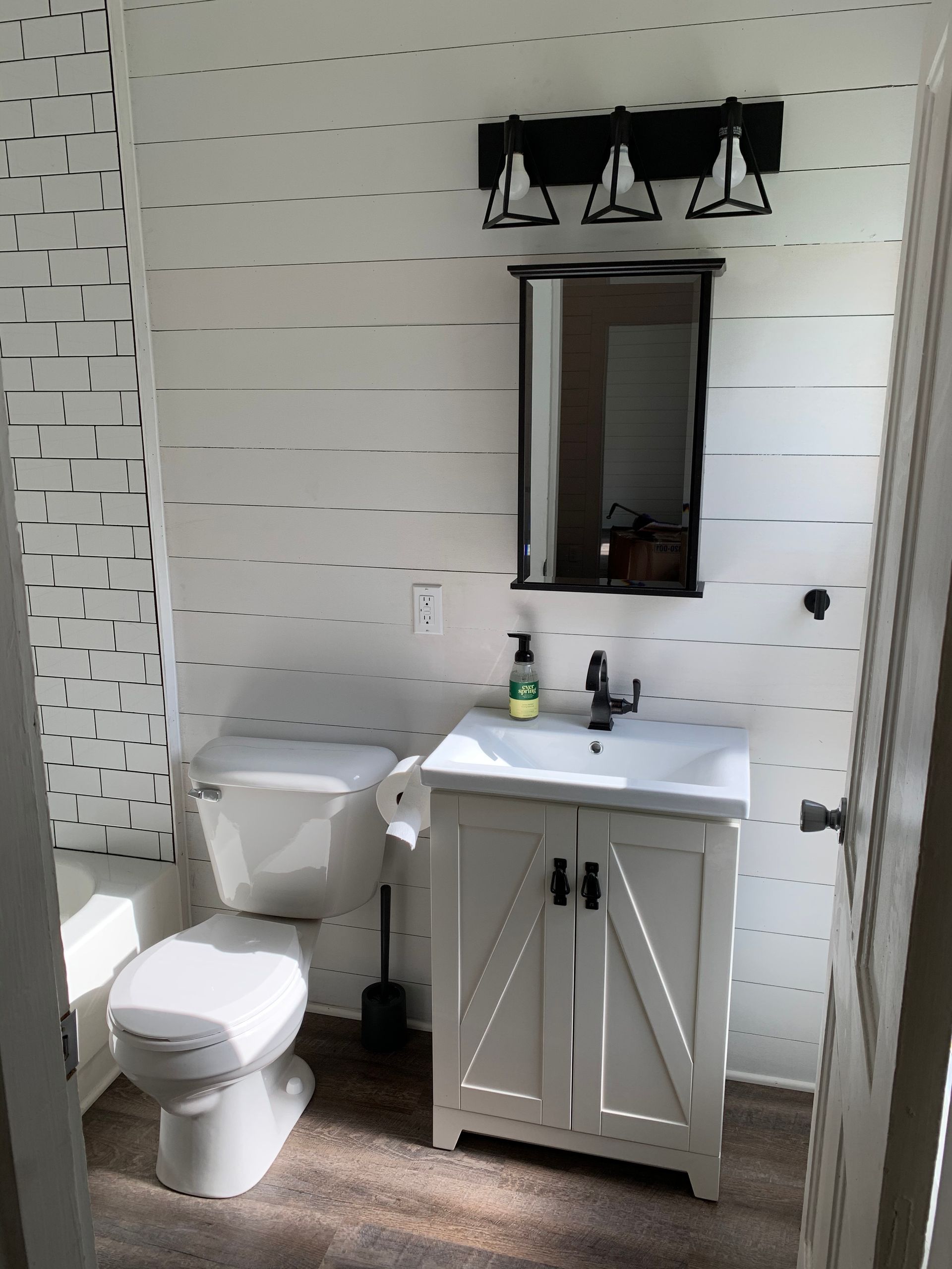 A bathroom with a toilet , sink and mirror.