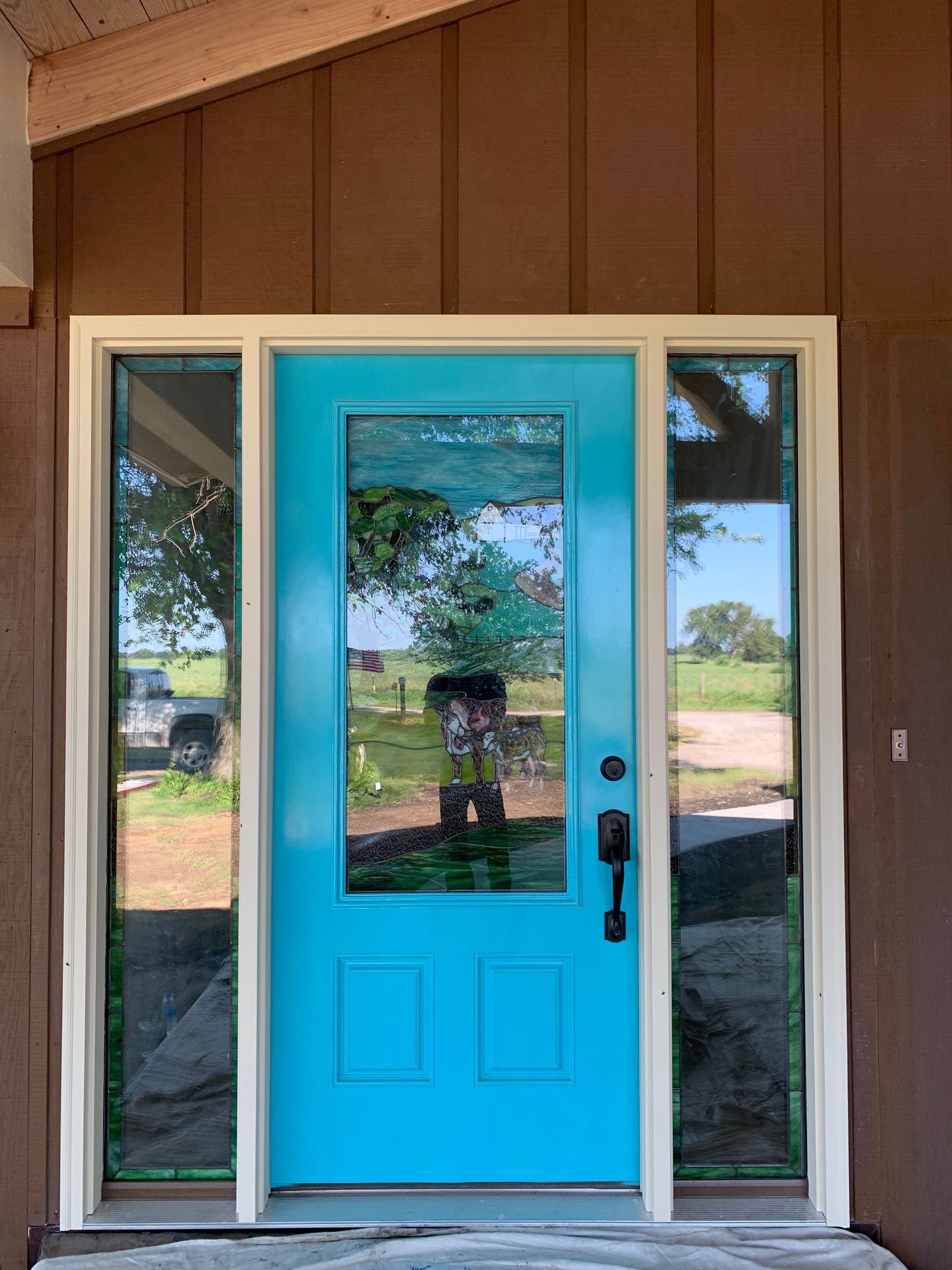 A blue door with a white trim is on a brown house.