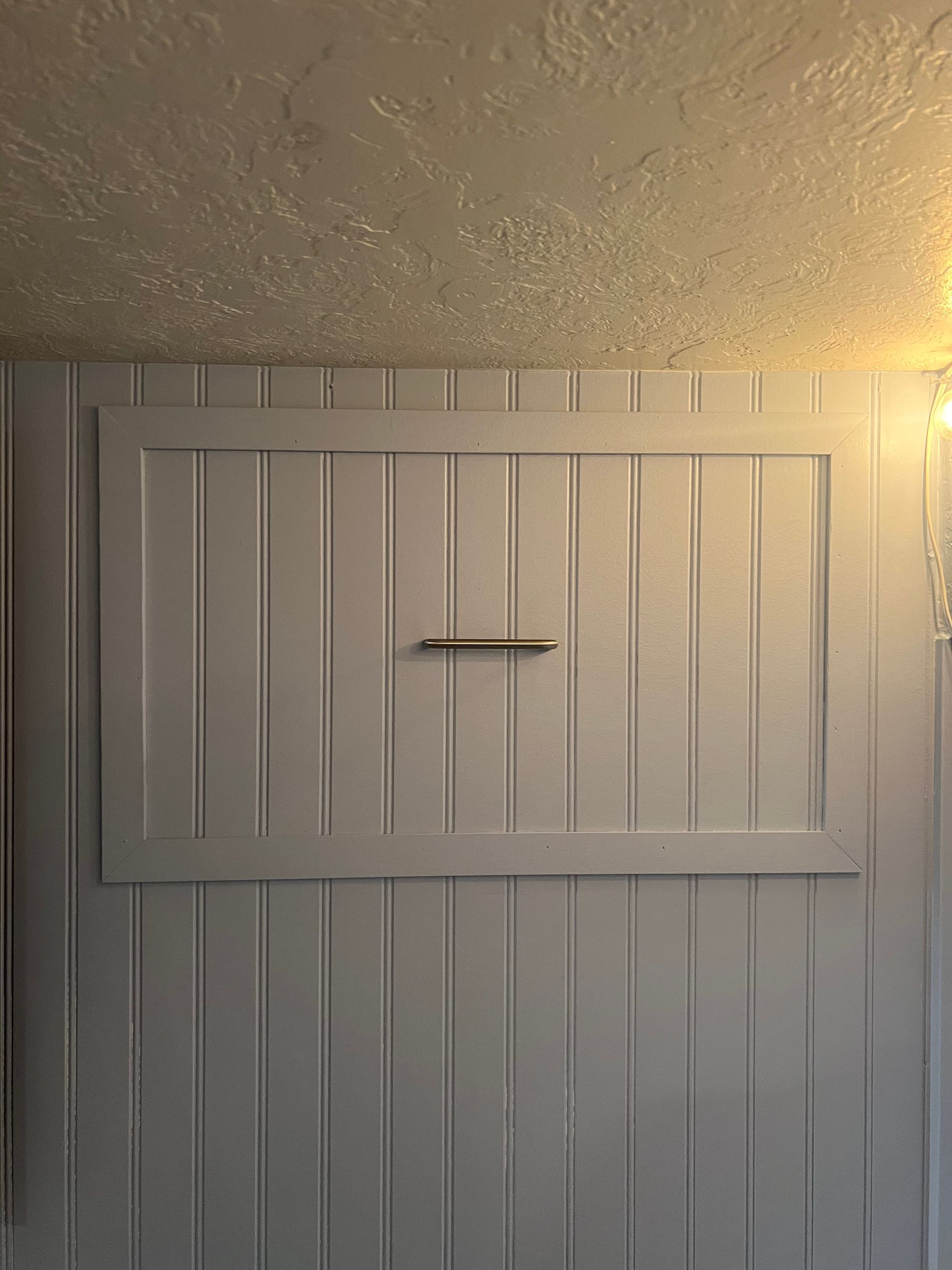 A white wall with a window in it and a light on the ceiling.